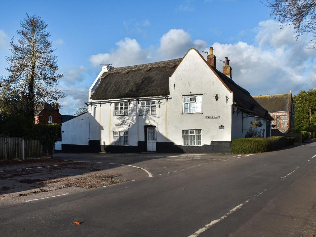 a white house with a black roof on a street at Stores Cottages in Ludham