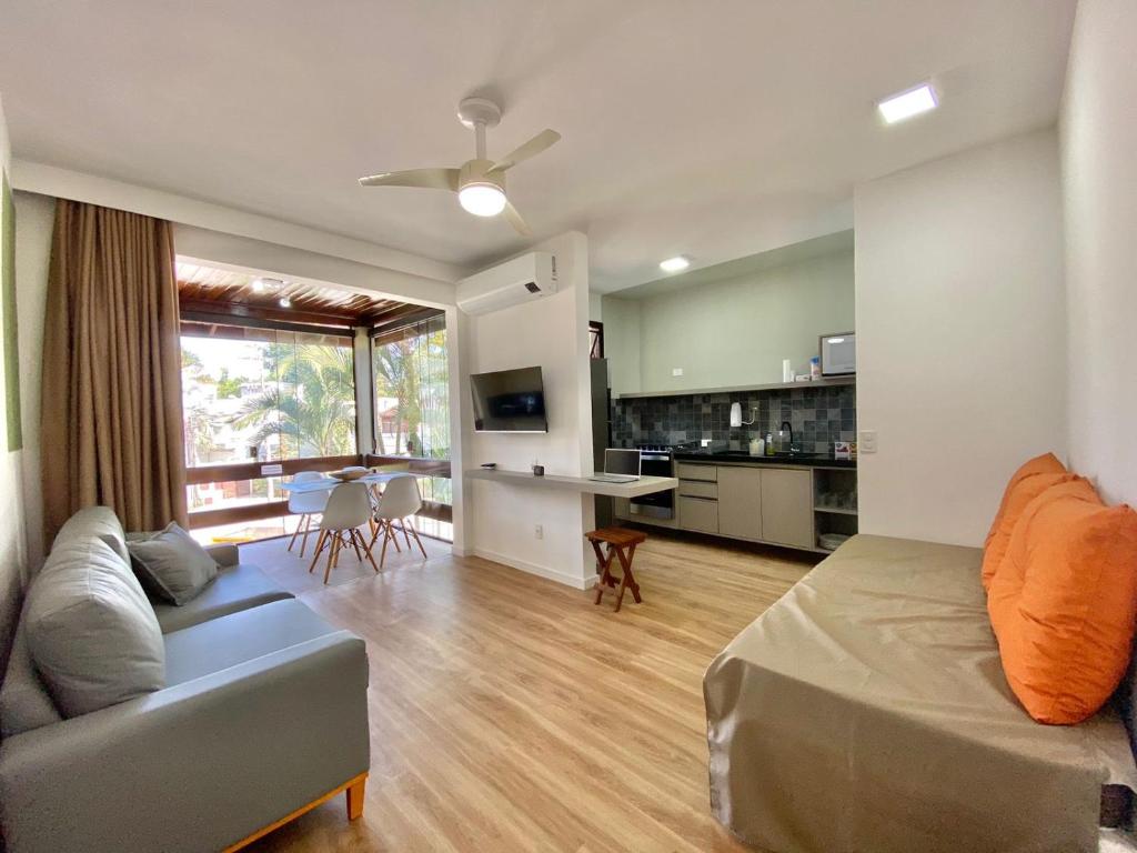 uma sala de estar com um sofá e uma sala de jantar em FLAT COM VARANDA E SERVIÇOS NO RIVIERA GREEN em Bertioga