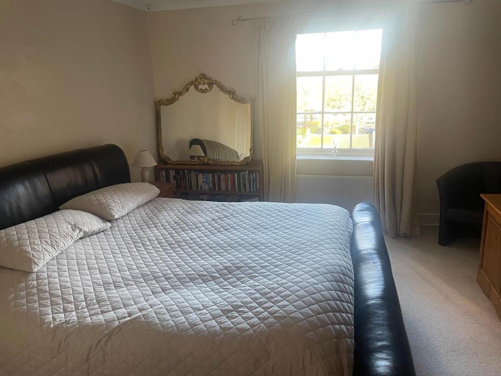 1 dormitorio con cama, espejo y ventana en Leamington Loft, en Leamington Spa