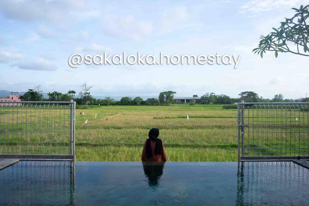 una mujer sentada en el agua frente a un campo en SakaLoka Villa - Banguntapan Yogyakarta, en Yogyakarta