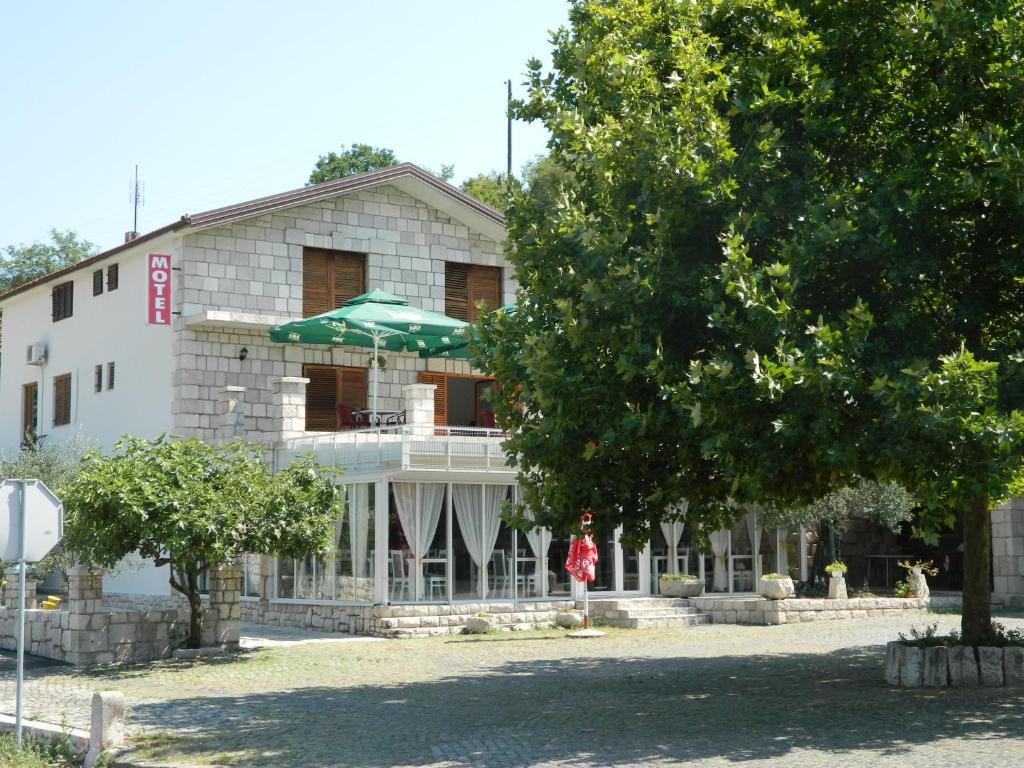 a woman standing in front of a building with an umbrella at Motel Jelčić in Čapljina