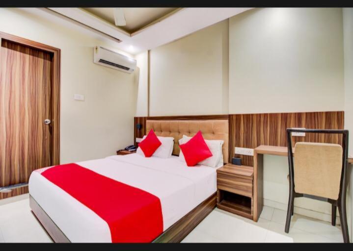 a bedroom with a red and white bed and a desk at Hotel Emerald Near T2 International Airport Mumbai in Mumbai