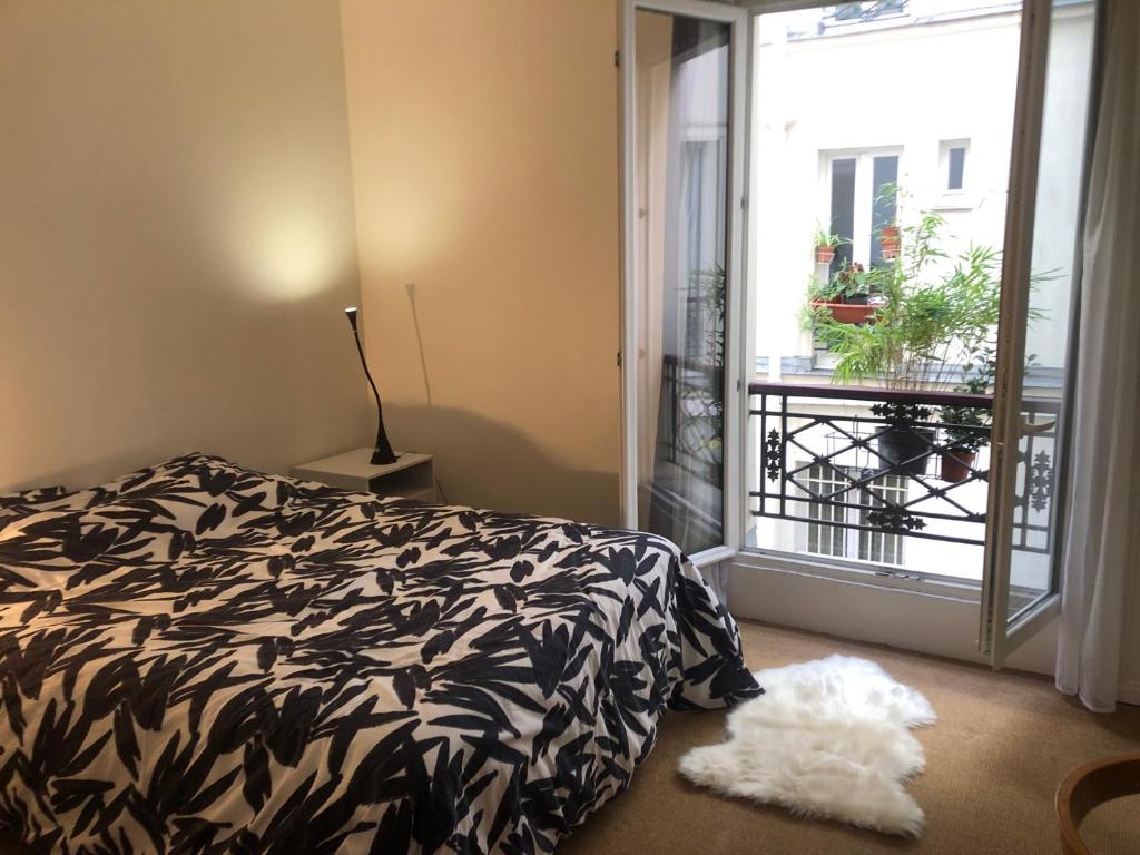 a bedroom with a black and white bed and a window at Chez Vero et Bruno in Paris