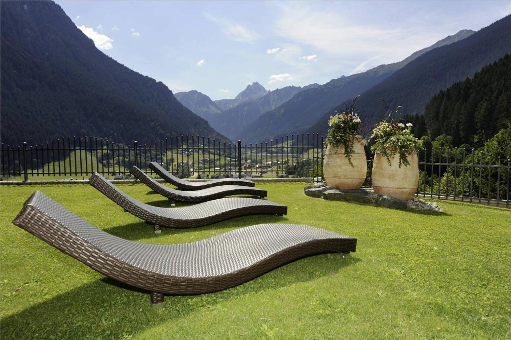 a group of benches sitting in the grass with mountains at Apart Alpenpension Maderer in Gaschurn