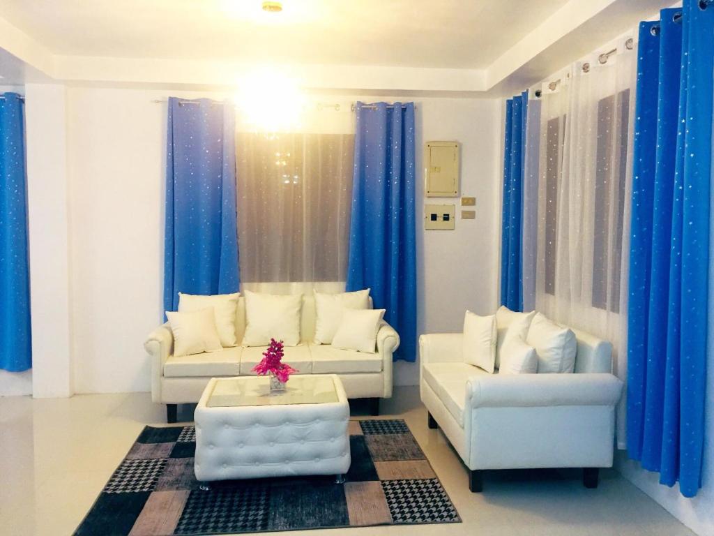 uma sala de estar com dois sofás e cortinas azuis em MGH Space Rental 
