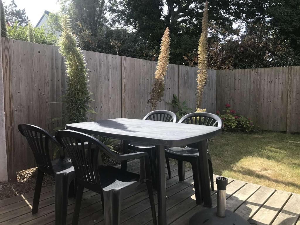 a table and four chairs on a deck with a fence at Appartement Trégastel, 3 pièces, 4 personnes - FR-1-368-45 in Trégastel