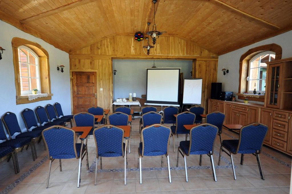 Small conference room with arranged blue chairs facing projection screen, wooden paneling and windows.