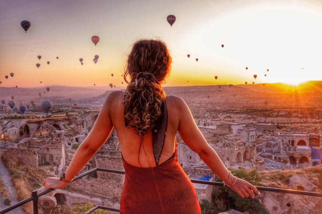 a woman in a red dress looking at hot air balloons at Takaev Cave House in Uçhisar