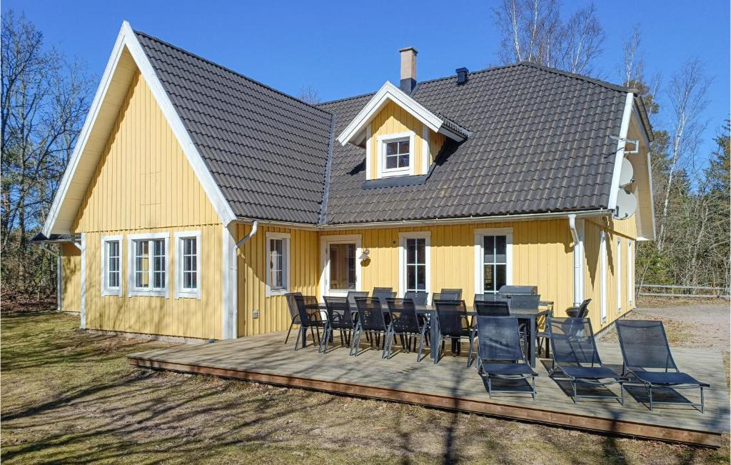uma casa amarela com cadeiras e uma mesa num deque em Beautiful Home In Kpingsvik With Sauna, Wifi And Indoor Swimming Pool em Grönskog