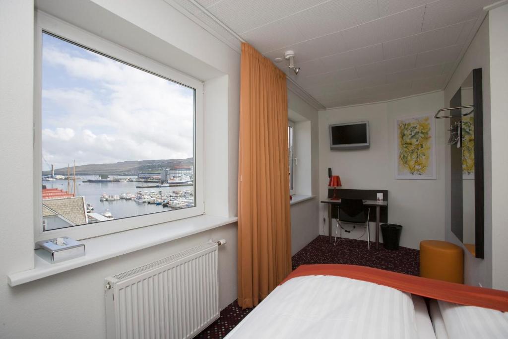 a bedroom with a window with a view of a harbor at Hotel Tórshavn in Tórshavn