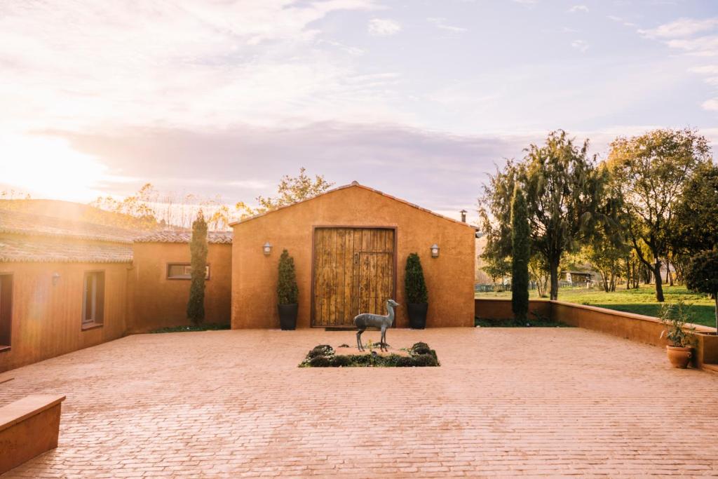 une maison avec une statue au milieu d'une allée. dans l'établissement Finca La Cruz de Piedra, à Matarrubia