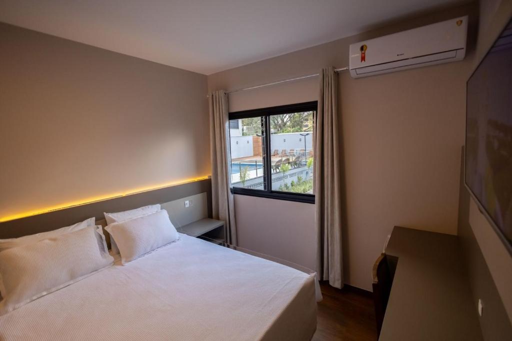 a bedroom with a white bed and a window at Safa Hotel Foz in Foz do Iguaçu