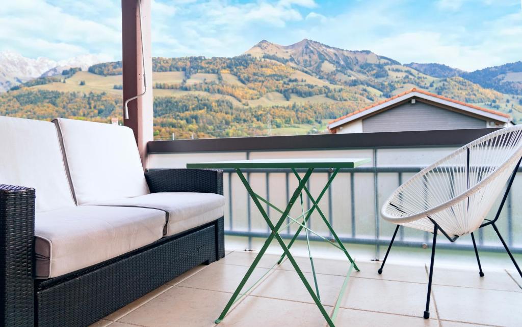 balcón con mesa, sillas y montañas en Appartement rénové 3chambres,Gruyère,3Parking,BBQ, en Neirivue