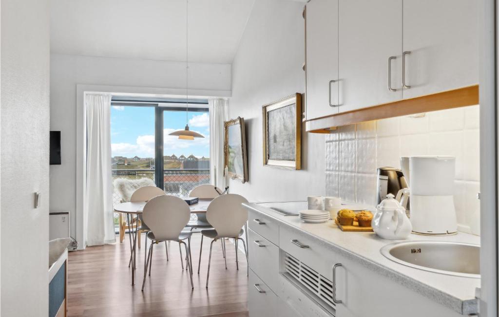 une cuisine avec des placards blancs et une table avec des chaises dans l'établissement Beautiful Apartment In Fan With Kitchen, à Fanø