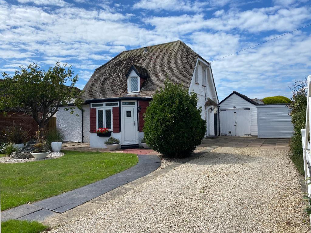 a white house with a gambrel roof and a driveway at Ocean Cottage, Ferring - seaside cottage moments from the beach and Bluebird cafe in Ferring
