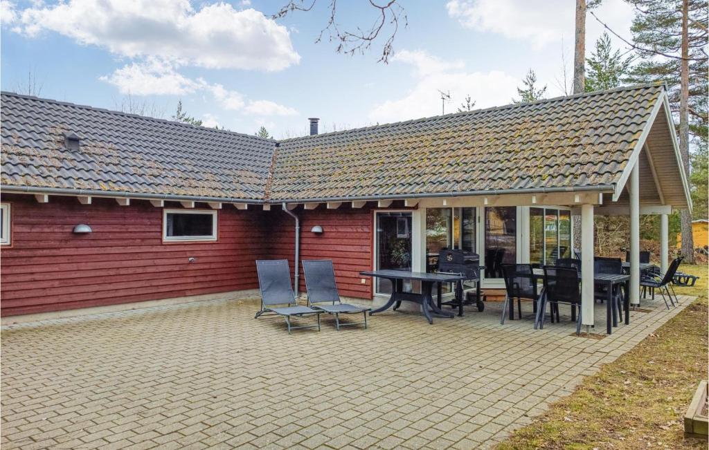 a red house with a patio with a table and chairs at Nice Home In Kpingsvik With Sauna in Grönskog