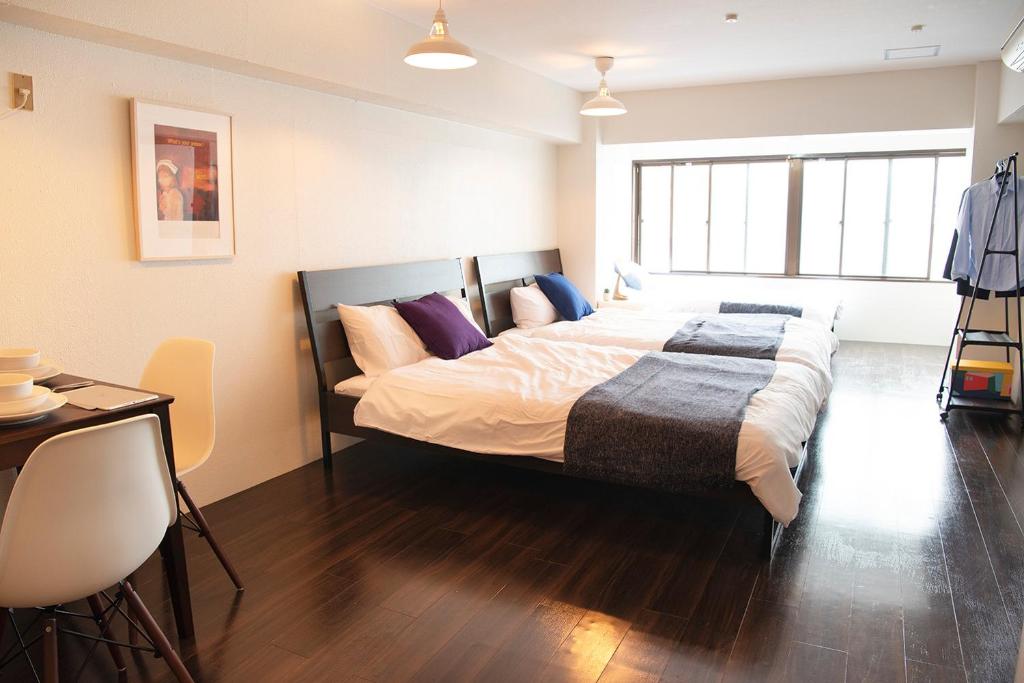 a large bed in a room with a table and chairs at #2 3stops to Shinjuku station stylish spacious studio apartment in Tokyo