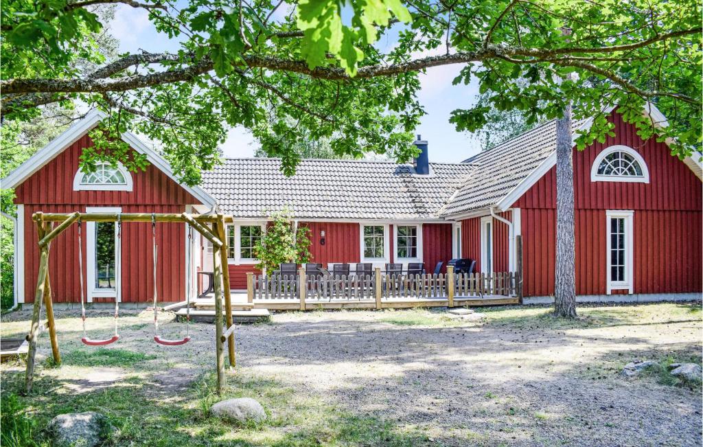 uma casa vermelha com um baloiço à frente dela em Amazing Home In Kpingsvik With Sauna em Köpingsvik