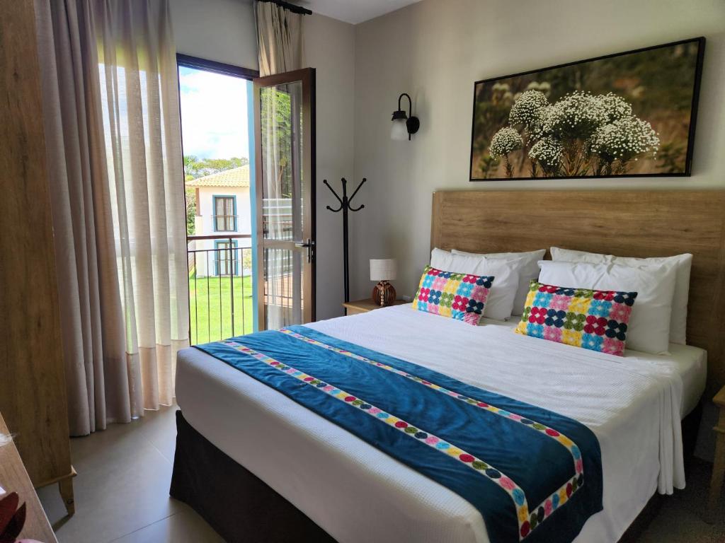 um quarto com uma cama grande e uma janela em Flat da Mata - Resort Quinta Santa Bárbara em Pirenópolis