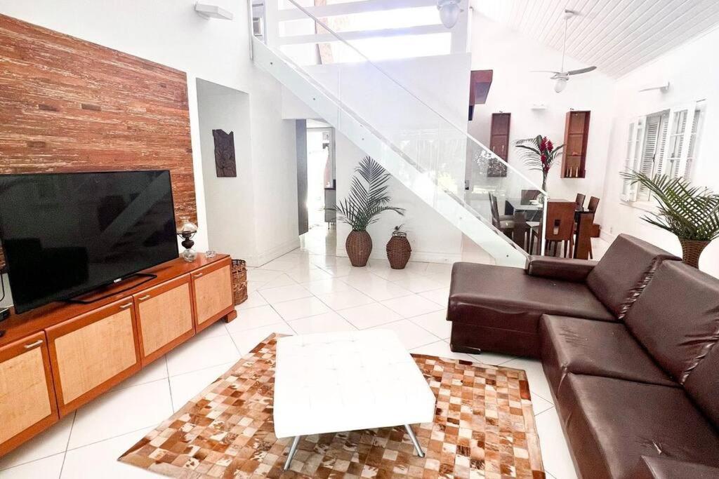 a living room with a couch and a flat screen tv at Paraíso de luxo: sua casa dos sonhos in Angra dos Reis