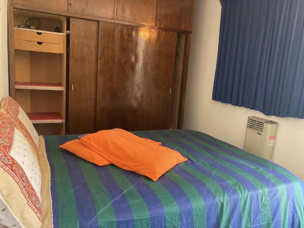 an orange pillow sitting on a bed in a room at Habitación con baño privado, barbacoa y entrada independiente en carrasco in Montevideo