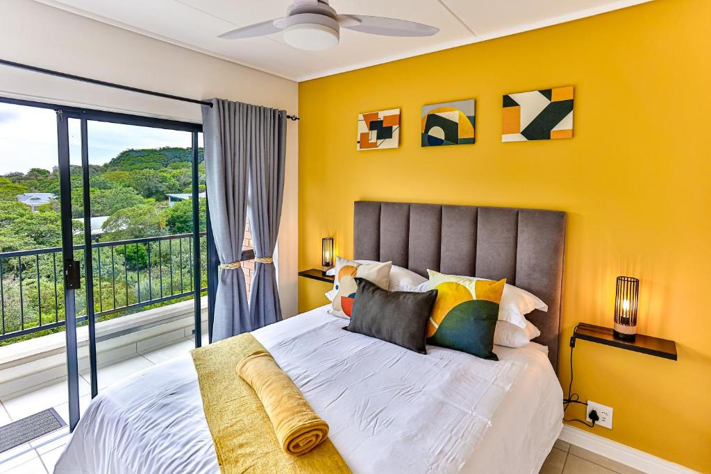 um quarto com uma cama com uma parede amarela em 572 Ballito Hills em Ballito