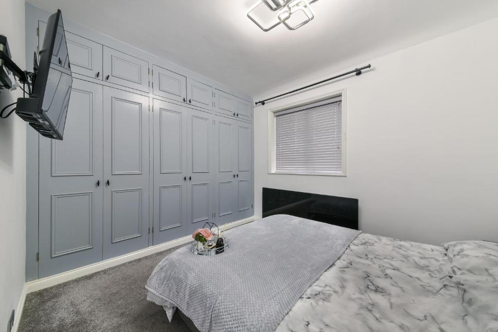 een witte slaapkamer met een bed en een televisie bij Bromley Palace - Entire 2 Bed House - Free Parking - Self Check-in in Londen