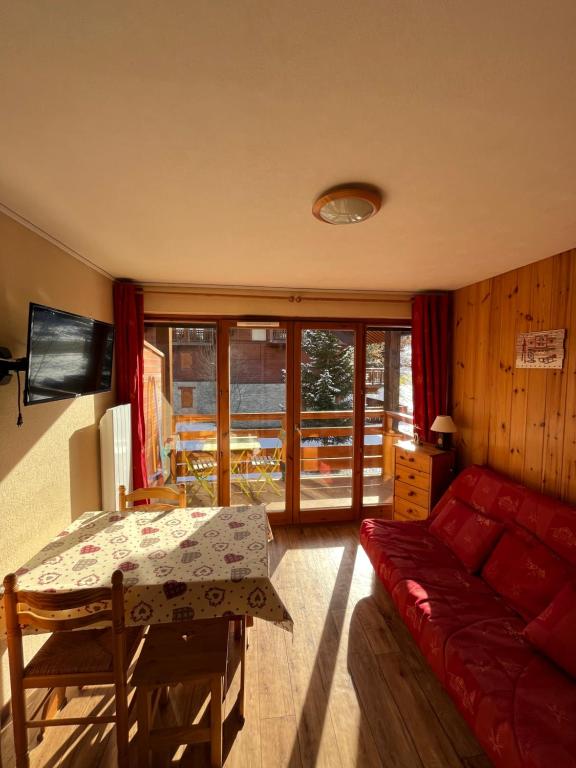 a living room with a red couch and a table at Appartement Valloire Galibier 4 personnes pied de piste in Valloire