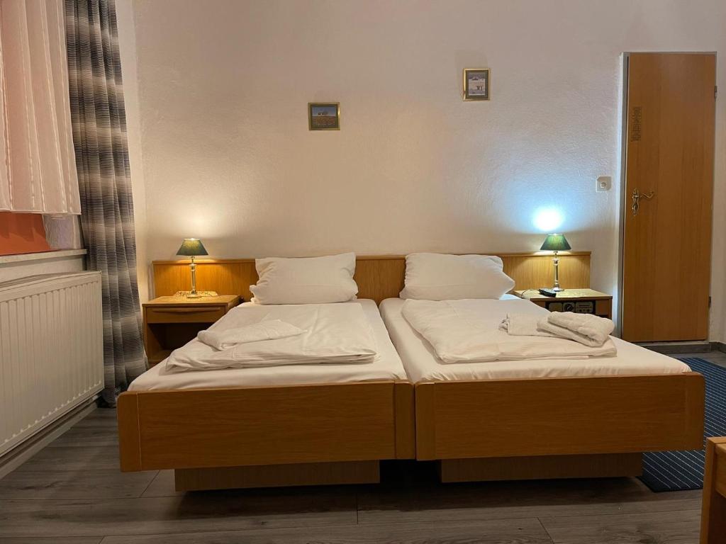 two beds in a room with two lamps on tables at Krügers Hotel in Barsinghausen