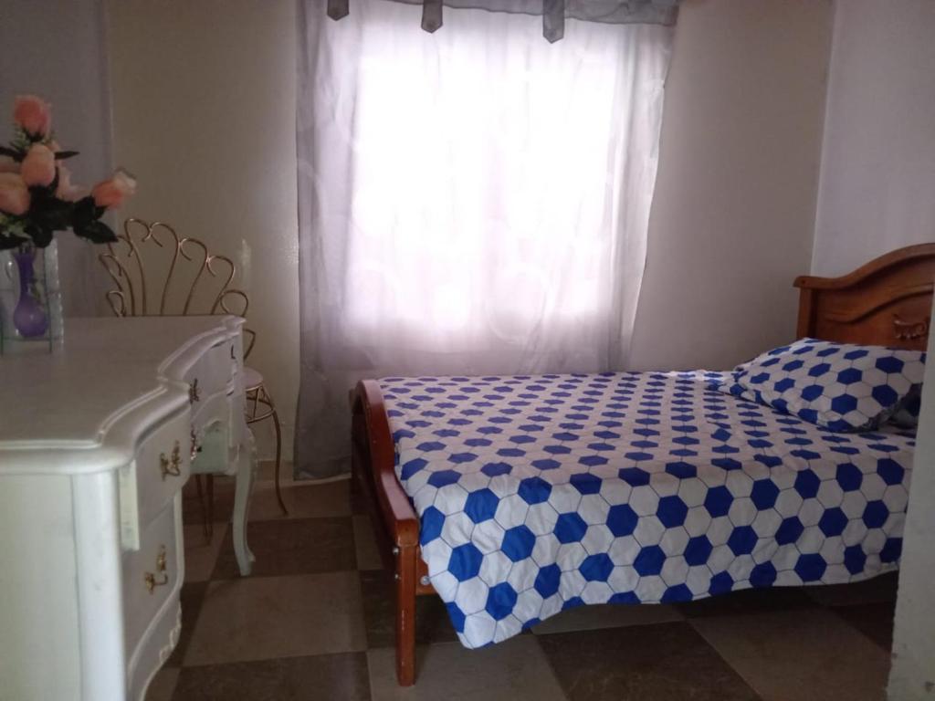 um quarto com uma cama com um cobertor xadrez azul e branco em Villa Leibrajo em Sasaima