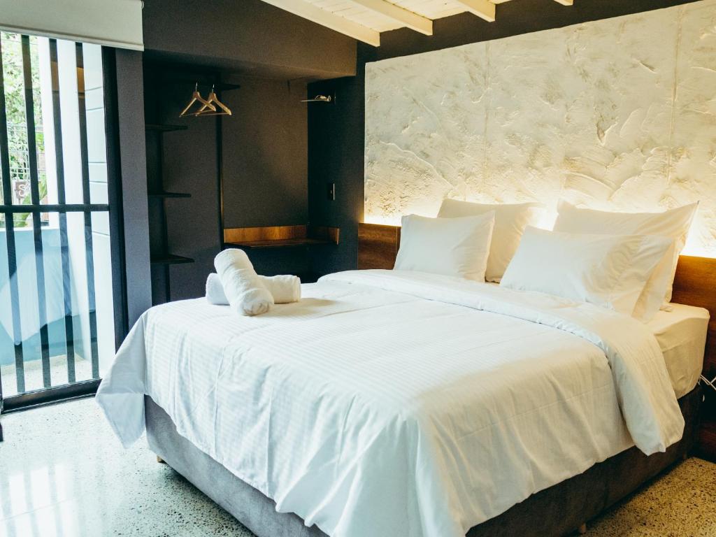 een slaapkamer met een groot bed met witte lakens bij I Believe- All Suite Manila-Poblado in Medellín