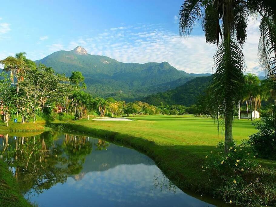 a golf course with a river and mountains in the background at house with swimmingpool, sauna and games room. in Angra dos Reis