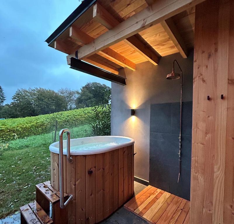 una bañera de hidromasaje en una terraza bajo un techo en Cabanes avec jacuzzi les pieds dans la vignes, 