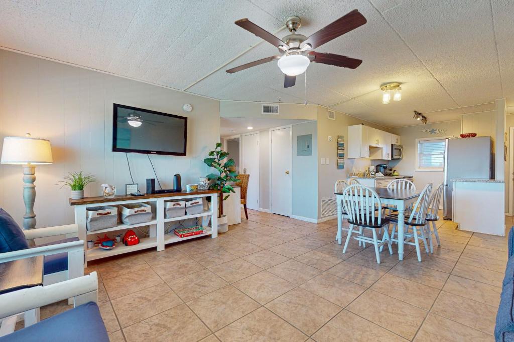 a living room with a ceiling fan and a dining room at IR 110: Seas the Day Port A: 2BR, 2BA, Shared Pool, Boardwalk to Beach, Golf Cart Access in Port Aransas
