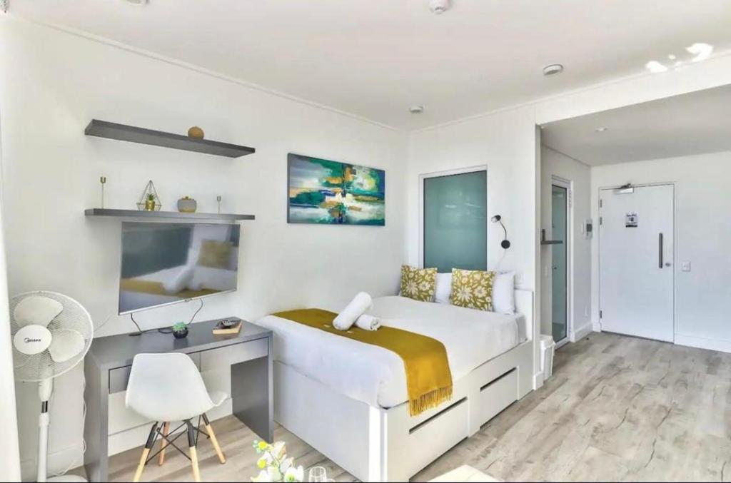 a white bedroom with a bed and a desk at Modern Luxe Getaway for 2 with Stunning Cape Town Views, Fast WiFi, Queen Bed, Voice Control, Chic & Stylish Comfort in Cape Town