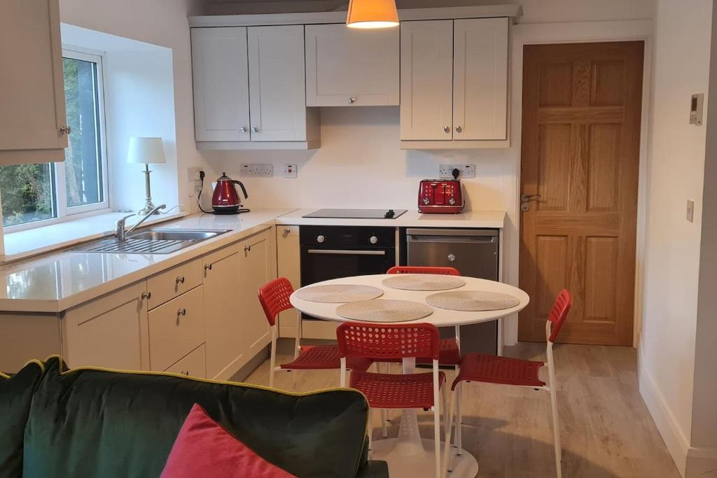 uma cozinha com uma mesa e cadeiras numa cozinha em Petit Lough Arrow cottage 