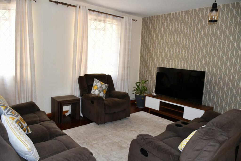 een woonkamer met een bank en een flatscreen-tv bij Stawi Apartment in Nairobi
