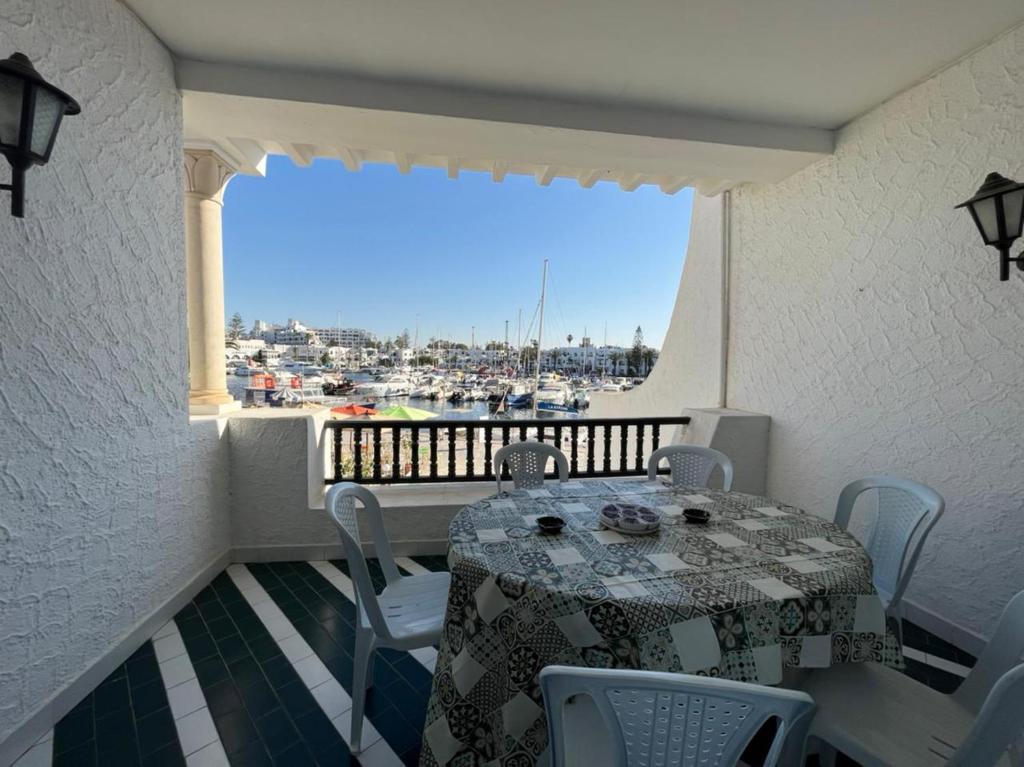 a table and chairs on a balcony with a view of a harbor at Appartement maria marina in Sousse