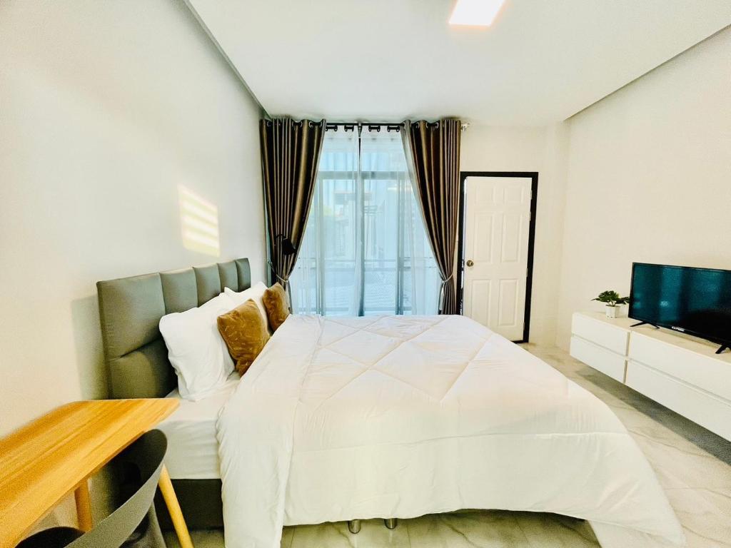a bedroom with a white bed and a television at Sky View Home and Hostel Chiangmai in Chiang Mai