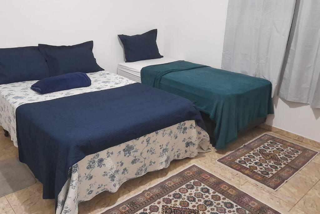 two beds in a room with blue and green sheets at Casa com 3 quartos in Itu