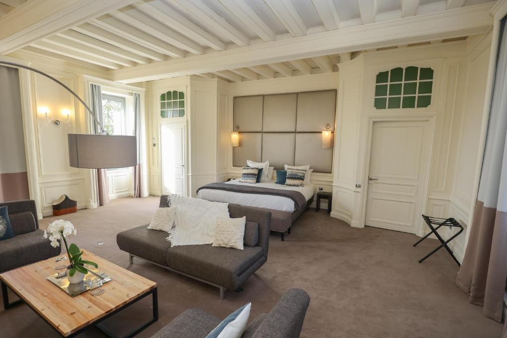 een hotelkamer met 2 bedden en een bank bij Hôtel Château de Lacan in Brive-la-Gaillarde