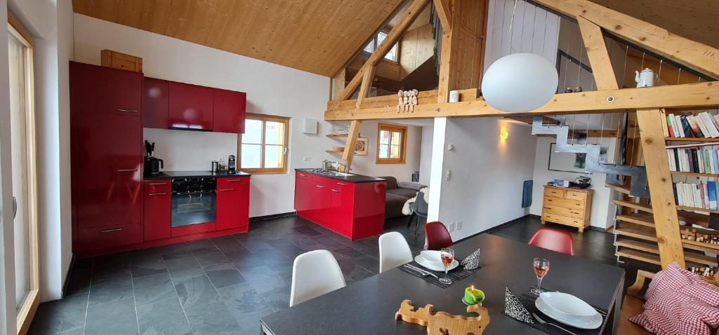 uma cozinha com armários vermelhos e uma mesa num quarto em Schönste Ferienwohnung mit Panoramablick in Ftan im Unterengadin em Ftan