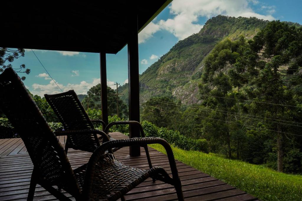 two chairs on a deck with a view of a mountain at Chalé Vista da Pedra in Gonçalves