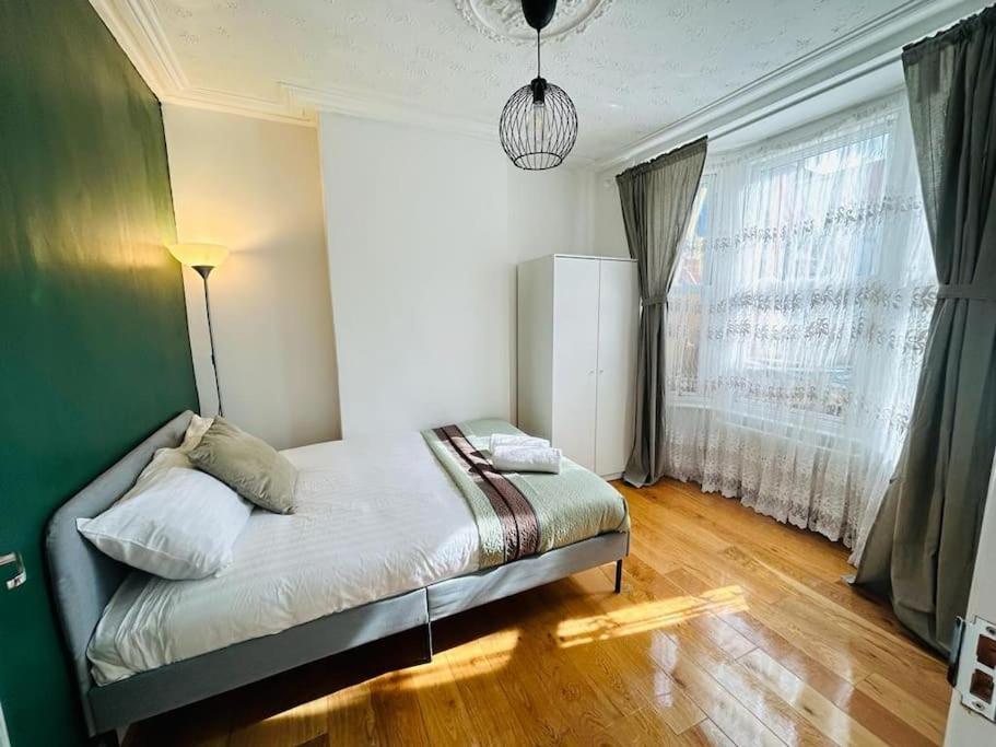 um quarto com uma cama e uma grande janela em Elegant House in Stratford em Londres