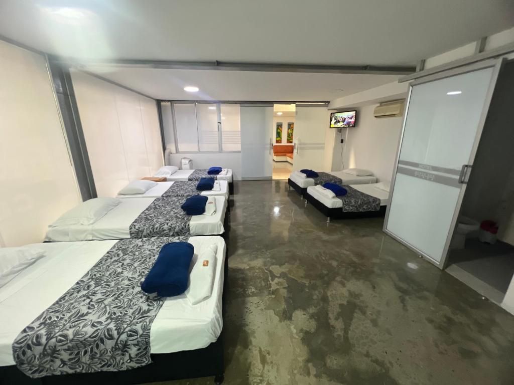 a row of beds in a room with blue pillows at Apartamento para grupos grandes dentro de centro comercial con frisby in Cartago