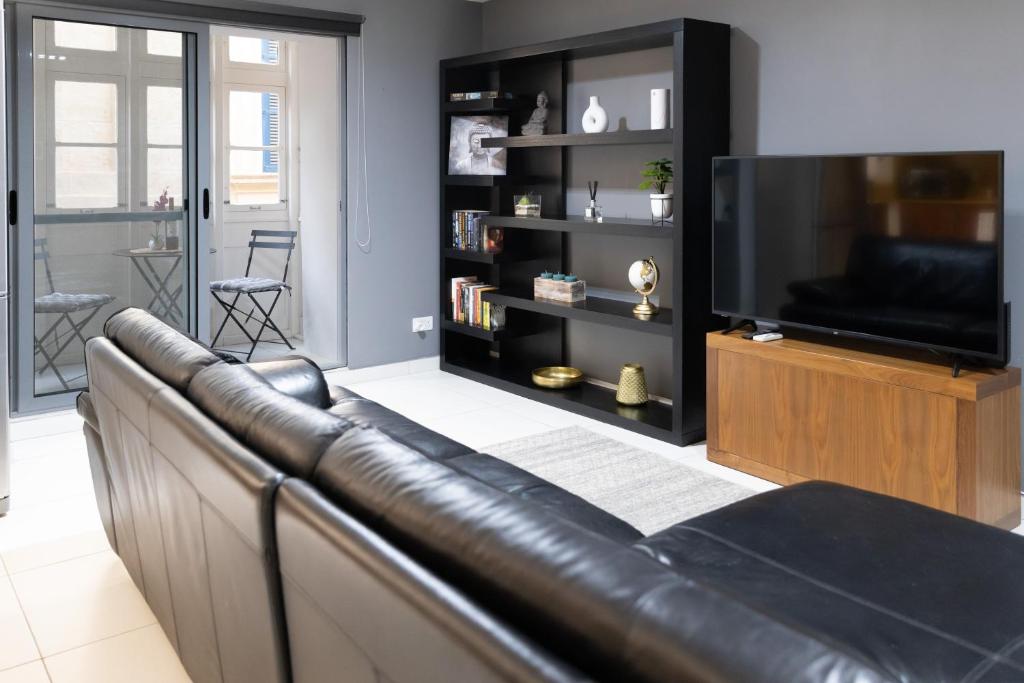 a leather couch in a living room with a television at Modern Central 2BR Flat in Valletta in Valletta