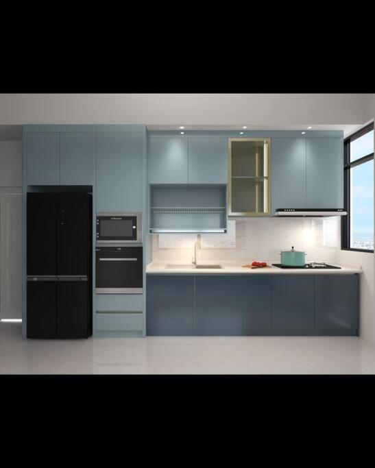 a kitchen with blue cabinets and a black refrigerator at Lee Batu Ferringhi Condominium in Batu Ferringhi
