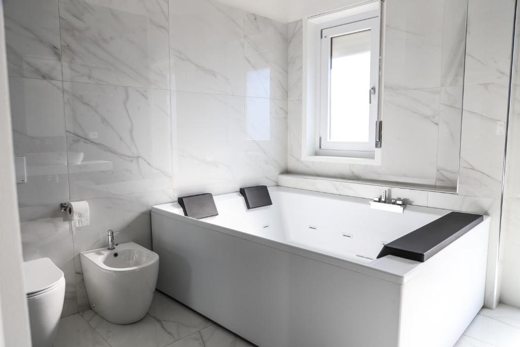 ein weißes Bad mit einer Badewanne und einem WC in der Unterkunft Concept Apartment in Belpasso