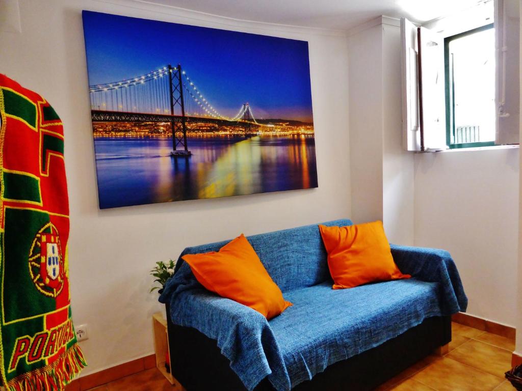 um sofá azul num quarto com uma pintura de uma ponte em Apartamento Embaixador Mateus em Lisboa