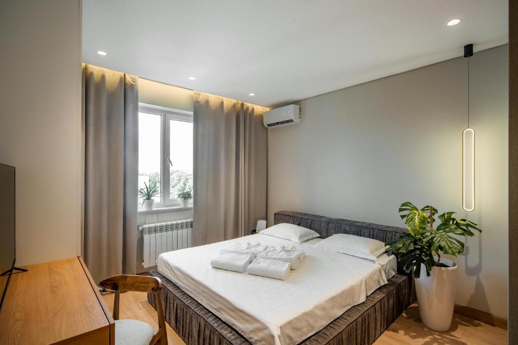Schlafzimmer mit einem Bett mit weißer Bettwäsche und einem Fenster in der Unterkunft Deluxe Apartment in Taschkent